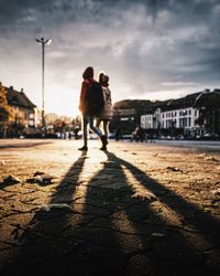 Silhouette woman with umbrella against sky in city