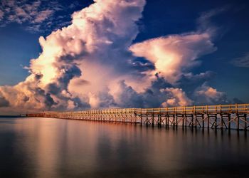 Bridge over sea against sky during sunset