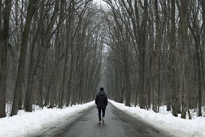 Rear view of man walking on road during winter