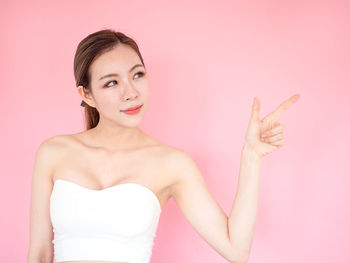 Portrait of young woman against pink background