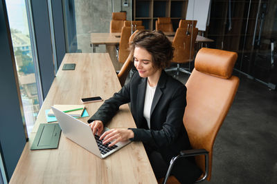 Young businesswoman using laptop while sitting in cafe