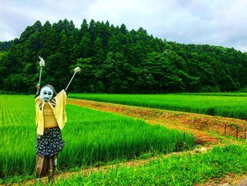 Scarecrow on field against trees in farm