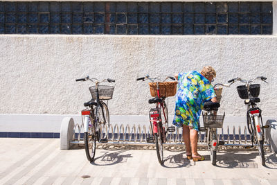 Woman standing amidst bicycles against building