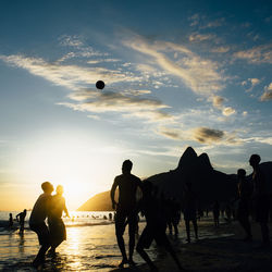 Silhouette people on beach against sky during sunset