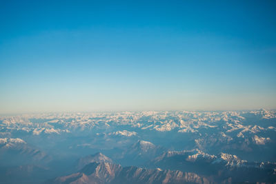 Aerial view of snowcapped mountains against blue sky