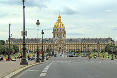People on street in front of hotel des invalides against sky