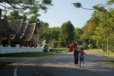 Full length of girl and women flying on road with thai traditional pavilion background