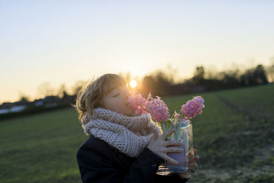 Boy on a meadow smelling hyacinth at sunset