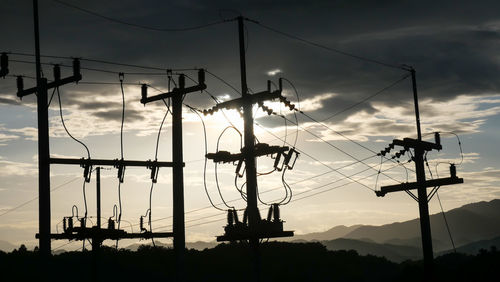 Low angle view of silhouette electricity pylon against sky during sunset