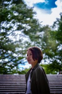 Portrait of a smiling young woman standing against trees