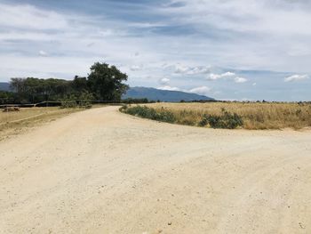 Road amidst field against sky