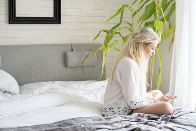 Young woman sitting on bed