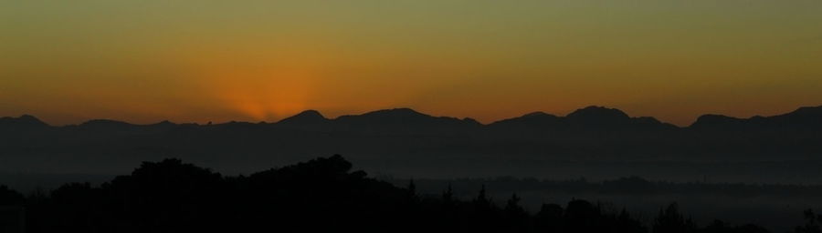 Scenic view of silhouette mountains against romantic sky at sunset