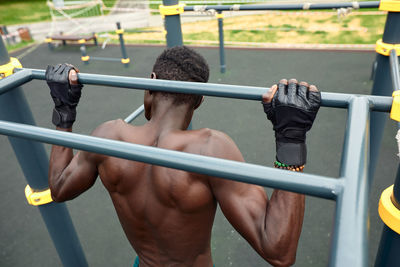 Rear view of shirtless man holding railing