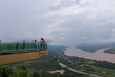 Tourists on skywalk at wat pha tak suea with mekong river in background