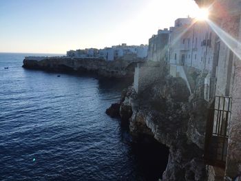 Buildings by sea against clear sky