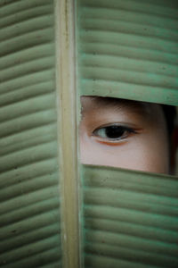 Close-up portrait of a serious hiding behind window