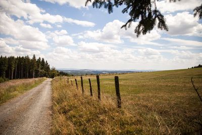 Road amidst field against sky