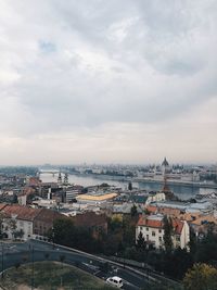 High angle view of city buildings against cloudy sky