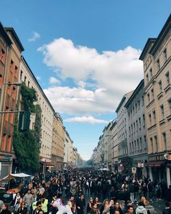 People on street amidst buildings in city against sky