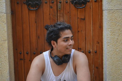 Portrait of smiling young man standing against door