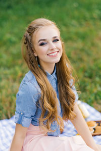Portrait of smiling young woman sitting on grassy field