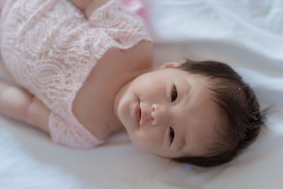 High angle portrait of baby girl lying on bed at home