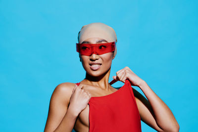 Portrait of young woman wearing mask against blue background