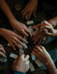 Cropped hands of friends playing dominoes on floor