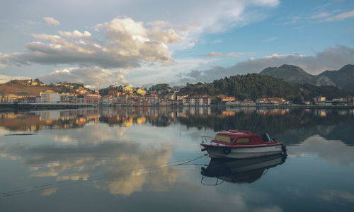 Boats in lake against sky in city