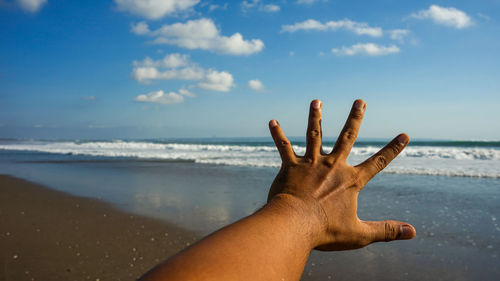 Midsection of person on sea shore against sky