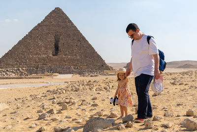 Father with daughter walking in front of the pyramid of mikerin on the giza plateau