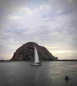 Sailboat sailing on sea against cloudy sky