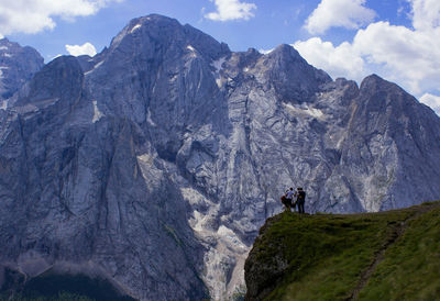Low angle view of hikers standing on cliff against rocky mountains
