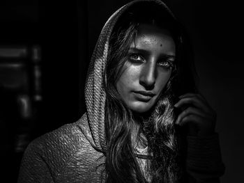 Close-up portrait of young woman against black background