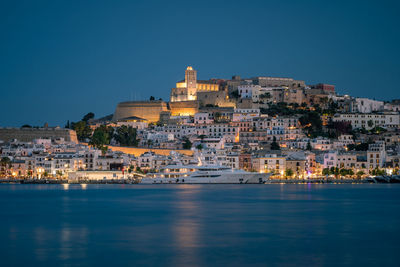 Buildings of ibiza city by sea against clear sky after sunset