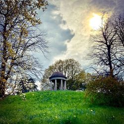 Built structure on field by trees against sky