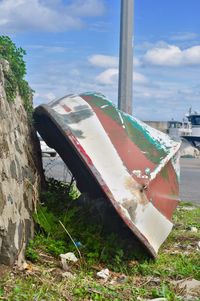 Close-up of abandoned boat moored on shore against sky