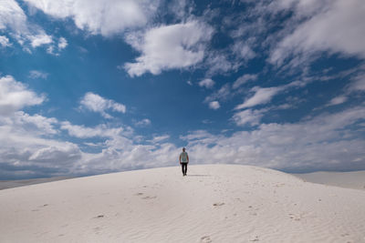 Man on sand dune in desert against sky