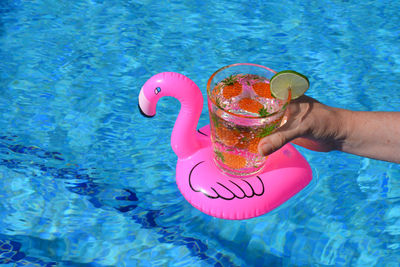 Midsection of person holding ice cream in swimming pool