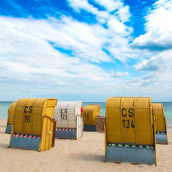 Hooded chairs on beach against sky