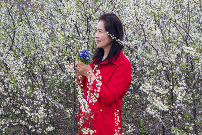 Woman standing by red flower tree