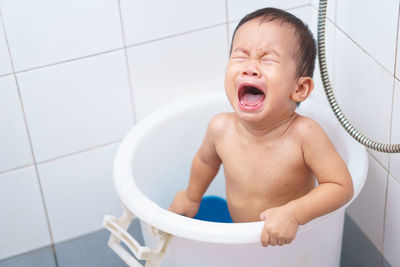 Boy crying in bucket at bathroom