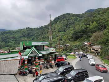 Vehicles on road by mountain against sky