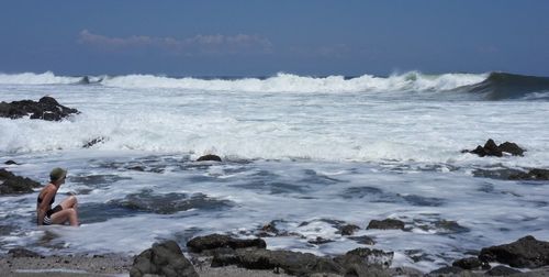 Woman sitting on rock at sea shore