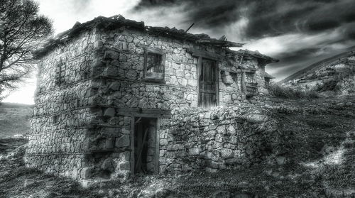 Low angle view of abandoned building against cloudy sky