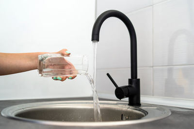 Cropped hand of woman emptying water in glass