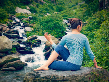 Rear view of man sitting on rock