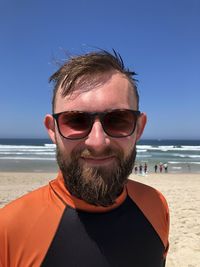 Portrait of man wearing sunglasses on beach against sky