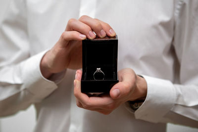 A young man holds in his hands a jewelry box with a diamond ring inside